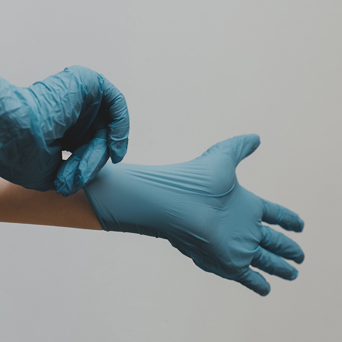 Hands putting on medical grade gloves